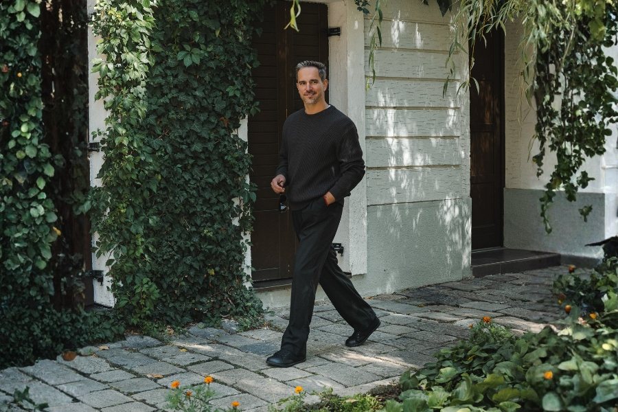 in black men's vegan barefoot shoes walking on paving by an ivy-covered house