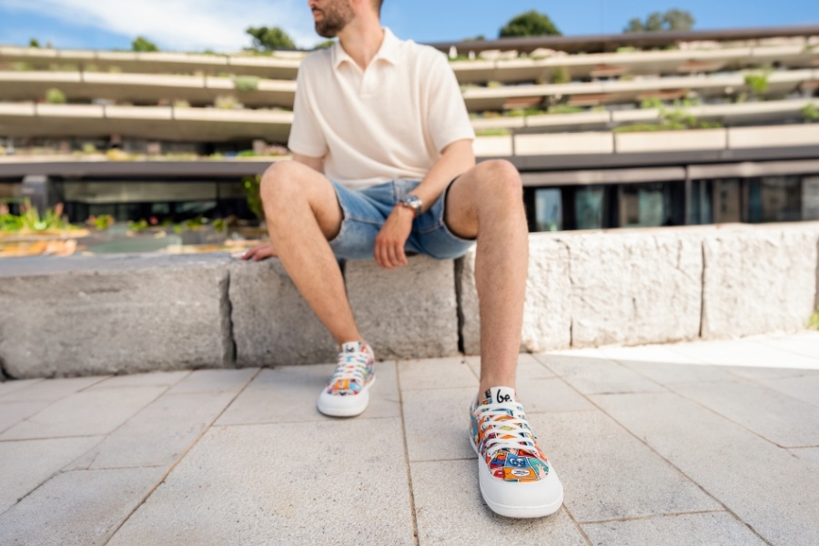 Man in colourful patterned men's vegan barefoot shoes sitting on a wall