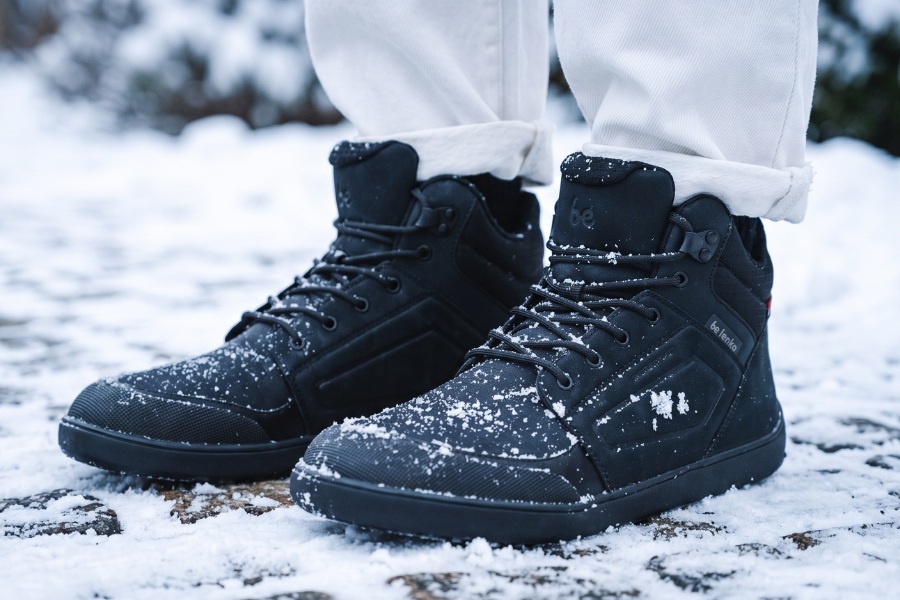 Nahaufnahme schwarzer Barfuß-Winter-Herrenschuhe mit Schnürung im Schnee Nahaufnahme schwarzer Barfuß-Winter-Herrenschuhe mit Schnürung im Schnee
