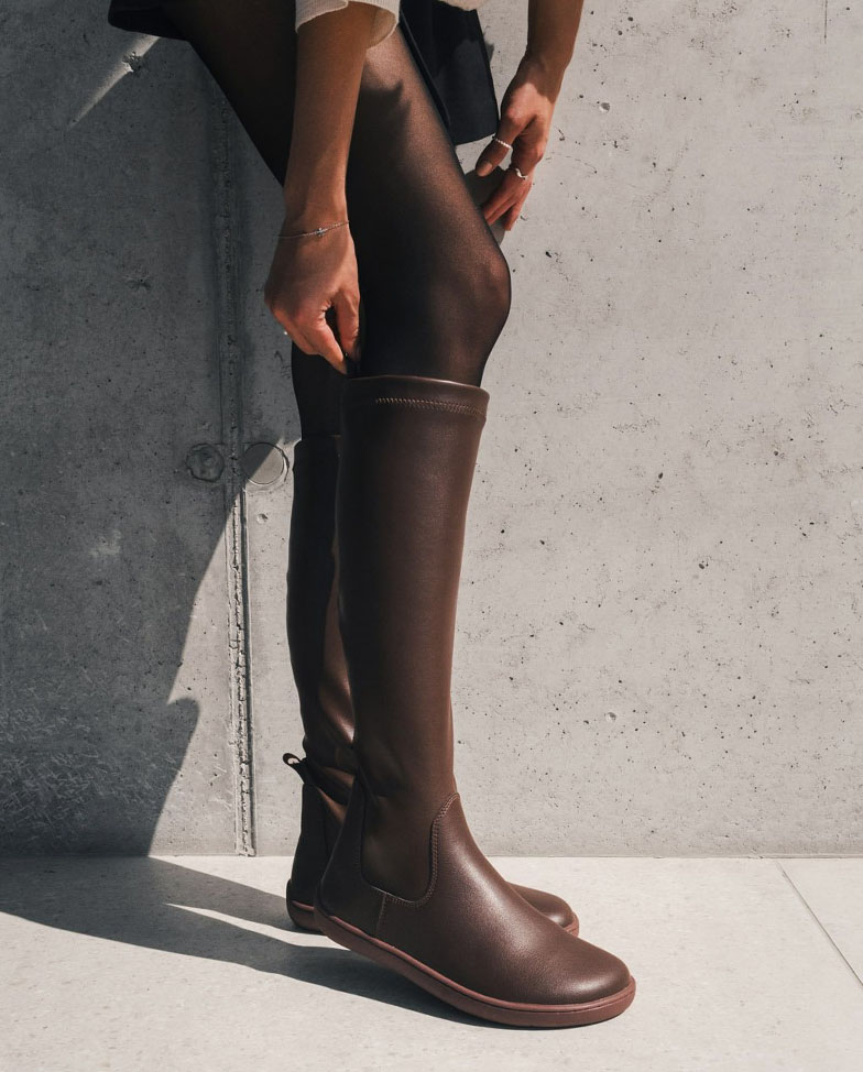 Be Lenka Athena - Chocolate, Barfuß-Kniestiefel, Frau zieht den Stiefel an
